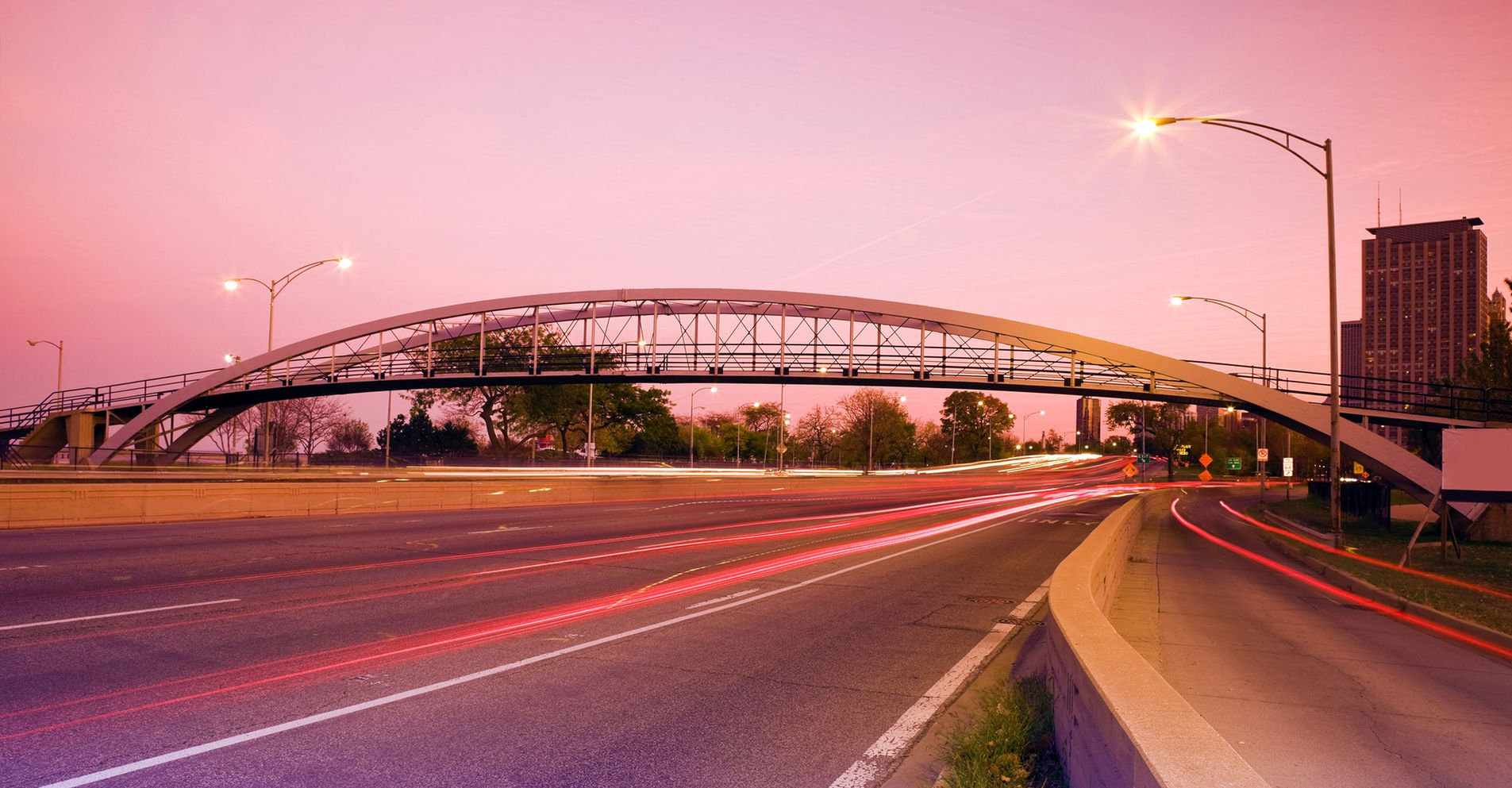 Dusk over a city corridor lit in pink